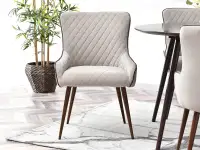 Krzesło z pikowaniem EMANU BEŻOWE tapicerowane do salonu - w aranżacji z regałami JENS i stołem TILIA